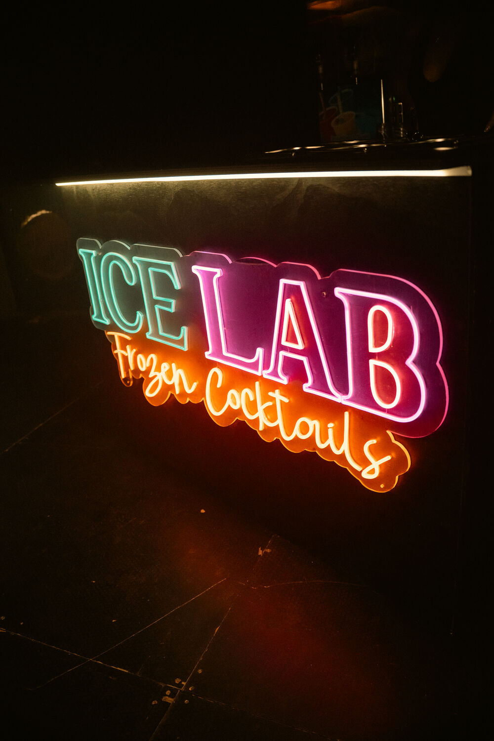 Barra de ICE LAB con el rótulo de neón Frozen Cocktails encendido por la noche